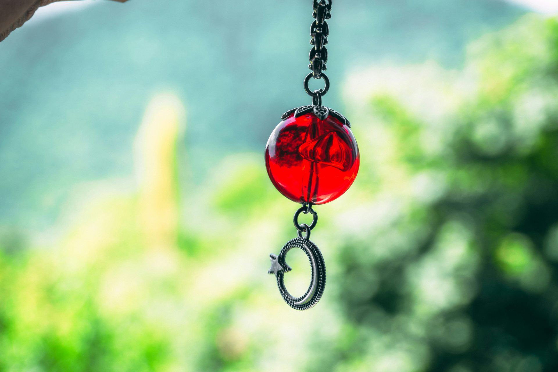 Eine rote Glasperle mit einem silbernen Halbmondanhänger.